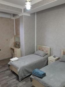 a bedroom with two beds and a table in it at Butik in Ganja