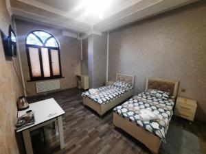a room with two beds and a desk and a window at Butik in Ganja
