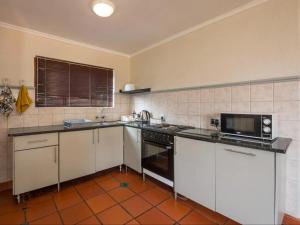 une cuisine avec des armoires blanches et un four à plaques de cuisson dans l'établissement 26 on Greenway, à White River