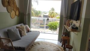 een woonkamer met een bank en een groot raam bij Seu refúgio em Maragogi in Maragogi