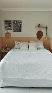 een slaapkamer met een groot wit bed met blauwe kussens bij Seu refúgio em Maragogi in Maragogi