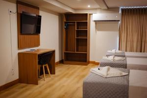 a room with two beds and a desk and a television at Amazon Seasons hotel in Belém
