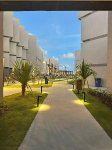 a sidewalk in front of a building with palm trees at Nomar Carneiros - Flat Beira-mar in Tamandaré