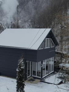 ein blaues Haus mit Schnee auf dem Dach in der Unterkunft GORY & TYSHA Гори і Тиша in Yavoriv