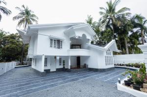 a white house with palm trees in the background at Bloom Fort Villa in Kannur