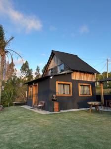 a black house with a bench in front of it at Cabana Rústica em Piedade in Piedade