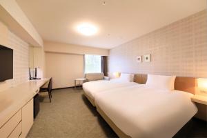 ein Hotelzimmer mit zwei Betten und einem Schreibtisch in der Unterkunft Richmond Hotel Fukushima Ekimae in Fukushima + 105 Fotos