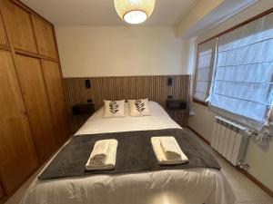 a bedroom with a large bed with two towels on it at Depto centrico soñado in San Martín de los Andes