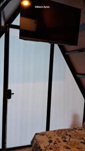 - une télévision à écran plat installée au-dessus d'un lit dans l'établissement Chalé Ecológico para 2 pessoas, à Bombinhas