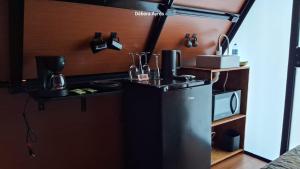 une petite cuisine avec un réfrigérateur et un micro-ondes dans l'établissement Chalé Ecológico para 2 pessoas, à Bombinhas