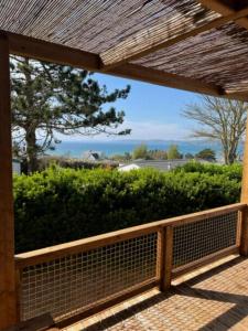 Eine Veranda mit Zaun und Blick auf einen Busch in der Unterkunft Camping 4 étoiles - Piscine - ccbegca in Créach-Guennou