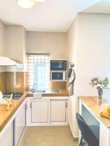 eine Küche mit weißen Schränken und einer Mikrowelle in der Unterkunft Zephyr House 3BR Pool, Rooftop & Ocean View in Grand-Gaube + 42 Fotos