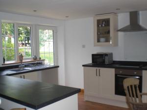 a kitchen with white cabinets and a black counter top at Bluebell and Appletree Cottages in Hockwold cum Wilton