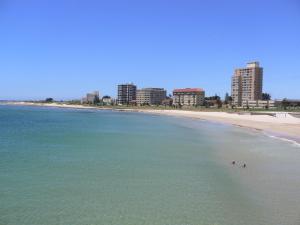 two people swimming in the ocean on a beach at At Sta-Plus Guest House in Port Elizabeth