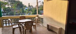 a balcony with a table and chairs and a window at Omkar Bungalow in Alibaug