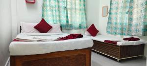 two twin beds in a room with red pillows at Omkar Bungalow in Alibaug