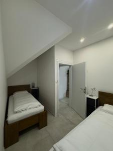 une chambre blanche avec deux lits et un lavabo dans l'établissement KARTAL centar apartment, à Bihać