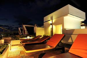 eine Dachterrasse mit Stühlen und ein Gebäude in der Nacht in der Unterkunft The Album Hotel in Patong Beach