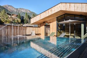 a house with a swimming pool in front of a building at Lärchenlodge SkySpa and Rooftop Pool inklusive Stubai SuperCard in Fulpmes