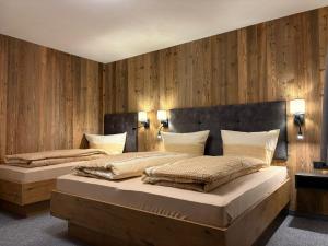 twee bedden in een kamer met houten lambrisering bij Alpenresort Panorama in Oberperfuss