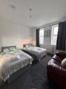 a bedroom with two beds and a couch in it at NextDoor Morden in Merton
