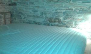 a white bed in a room with a stone wall at Patrika Traditional House in Patriká