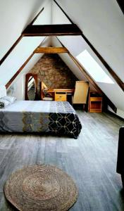 Schlafzimmer im Dachgeschoss mit einem Bett und einer Steinmauer in der Unterkunft Gîte CosyCool in Languidic