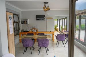 een eetkamer met een tafel en paarse stoelen bij 5@Partridge Guesthouse in Newcastle