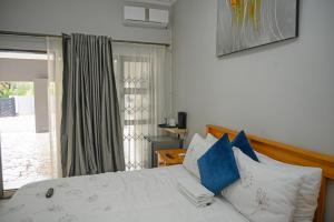 een slaapkamer met een bed met blauwe en witte kussens bij 5@Partridge Guesthouse in Newcastle +16 foto's