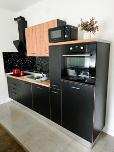 a kitchen with a black stove and a sink at Apartman Fratelli in Ljubuški