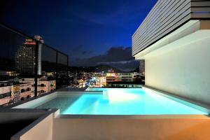 a swimming pool on the roof of a building at night at The Album Hotel in Patong Beach