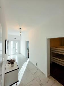 a white hallway with a table and a piano at Apartman Fratelli in Ljubuški