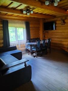 a dining room with a table and chairs and a television at Садиба для відпочинку in Vyshka