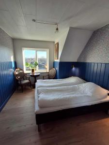 a bedroom with a bed and a table and a window at Vrensted Hostel B&B in Løkken