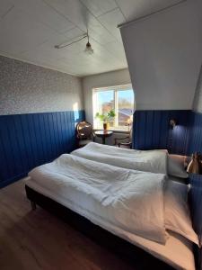 a bedroom with a large bed with a blue wall at Vrensted Hostel B&B in Løkken