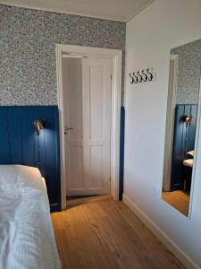 a bedroom with a white bed and a mirror at Vrensted Hostel B&B in Løkken