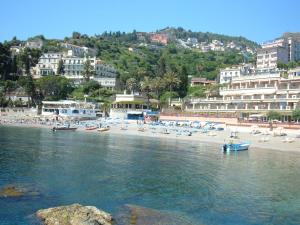 a beach with a group of people and a boat in the water at Taormina Bay Lucia's House Roccalumera in Roccalumera