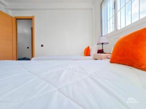 ein weißes Bett mit orangefarbenem Kissen darüber in der Unterkunft Entire condo hosted by Dar Al Khayma in Agadir + 21 Fotos