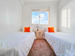 2 Betten in einem weißen Zimmer mit orangefarbenen Kissen in der Unterkunft Entire condo hosted by Dar Al Khayma in Agadir