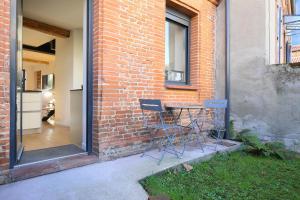 twee stoelen en een tafel naast een stenen muur bij NEW - Maison brique 4p - Côte Pavée coeur Toulouse in Toulouse +41 foto's