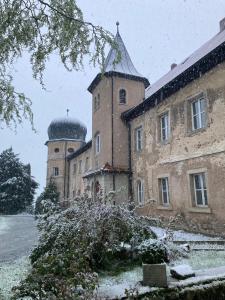 un vieux château sous la neige avec une tour et une tourelle dans l'établissement Schloss1611 B&B, à Erbendorf