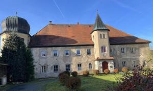 un vieux bâtiment en pierre avec une tourelle et un dôme dans l'établissement Schloss1611 B&B, à Erbendorf