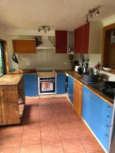 een keuken met blauwe kasten en een tegelvloer bij Dragon's den main house in Takaka