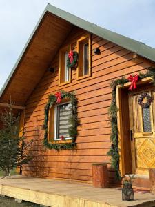 Una casa decorada para Navidad con coronas y una puerta. en EscapeTinyCabin by IezerVenture, en Lereşti 14 fotos más