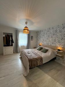 een slaapkamer met een groot bed en een kroonluchter bij Maison d'hôtes - La Forge de Clermont in Clermont