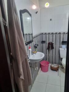 een badkamer met een wastafel, een toilet en een spiegel bij We'llcome home in Temara