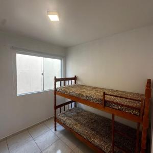 two bunk beds in a room with a window at Aconchego Litorâneo 2 in Piçarras