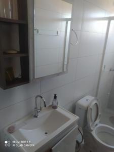 a bathroom with a sink and a toilet and a mirror at Aconchego Litorâneo 2 in Piçarras +7 photos