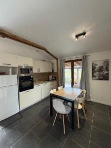 een keuken met een houten tafel en stoelen. bij Gîte Le Grand Landais - La Forge De Clermont in Clermont