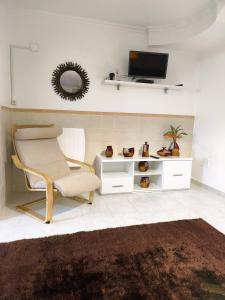 een woonkamer met een stoel en een tv bij ManelMar O Refúgio in Nazaré